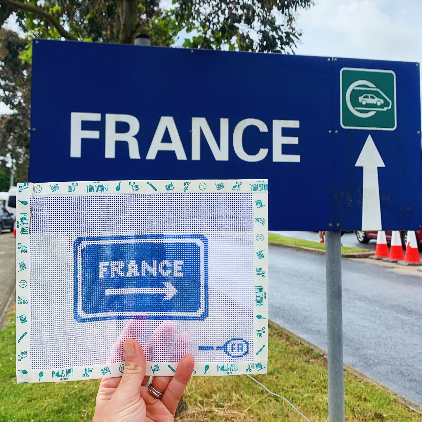 France This Way needlepoint canvas—black uppercase “FRANCE THIS WAY” text with a dashed-arrow motif on natural 14-HPI Zweigart canvas, 5 × 3″ DIY travel décor