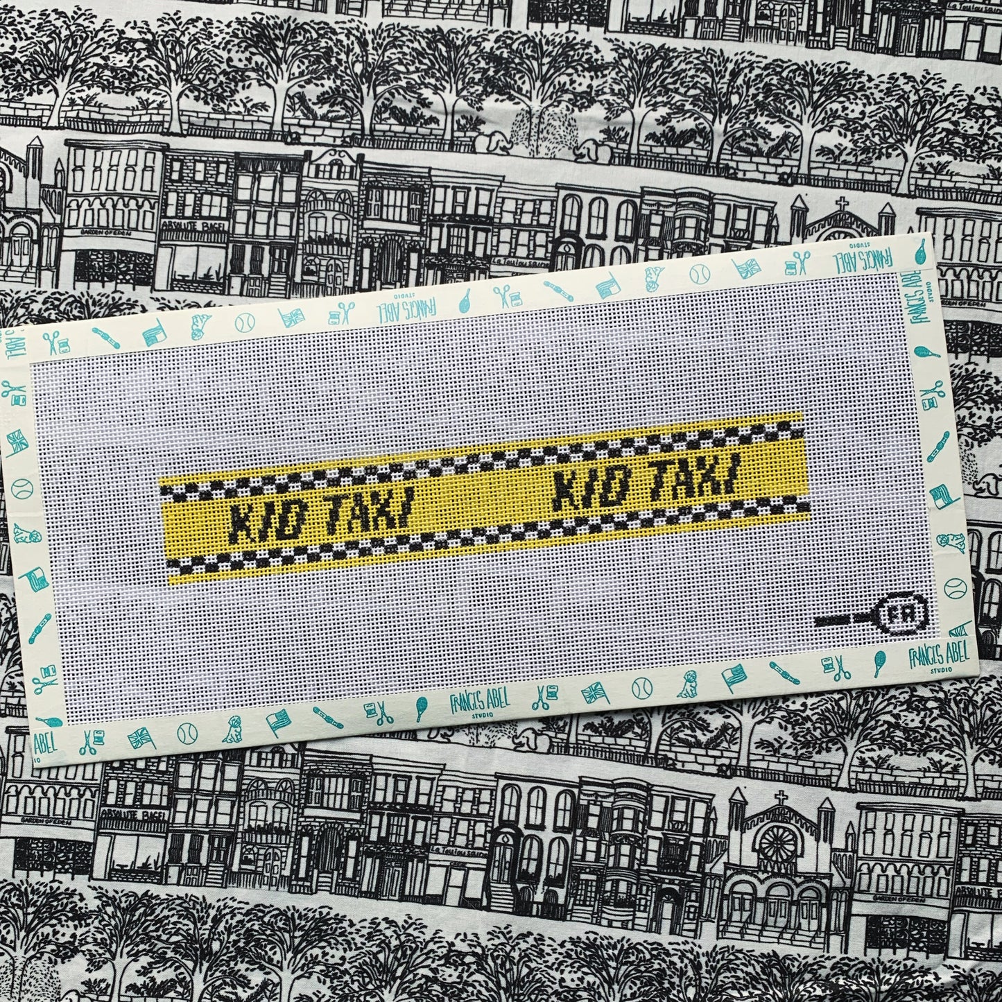 Kid Taxi key-fob needlepoint canvas—yellow checkered taxi stripe reading “KID TAXI,” 8.3 × 1.4″ on 13-mesh DIY project