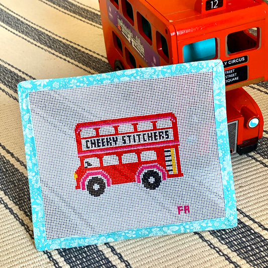 Cheeky Stitchers London Bus needlepoint canvas—red double-decker bus motif printed on natural 13-mesh canvas with turquoise floral-tape border 