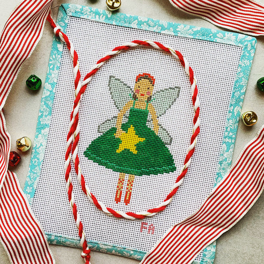  Christmas fairy needlepoint canvas featuring a ballerina-style fairy in a green dress holding a yellow star, with silver wings and a red headband, trimmed in aqua floral tape and surrounded by striped ribbon and jingle bells.