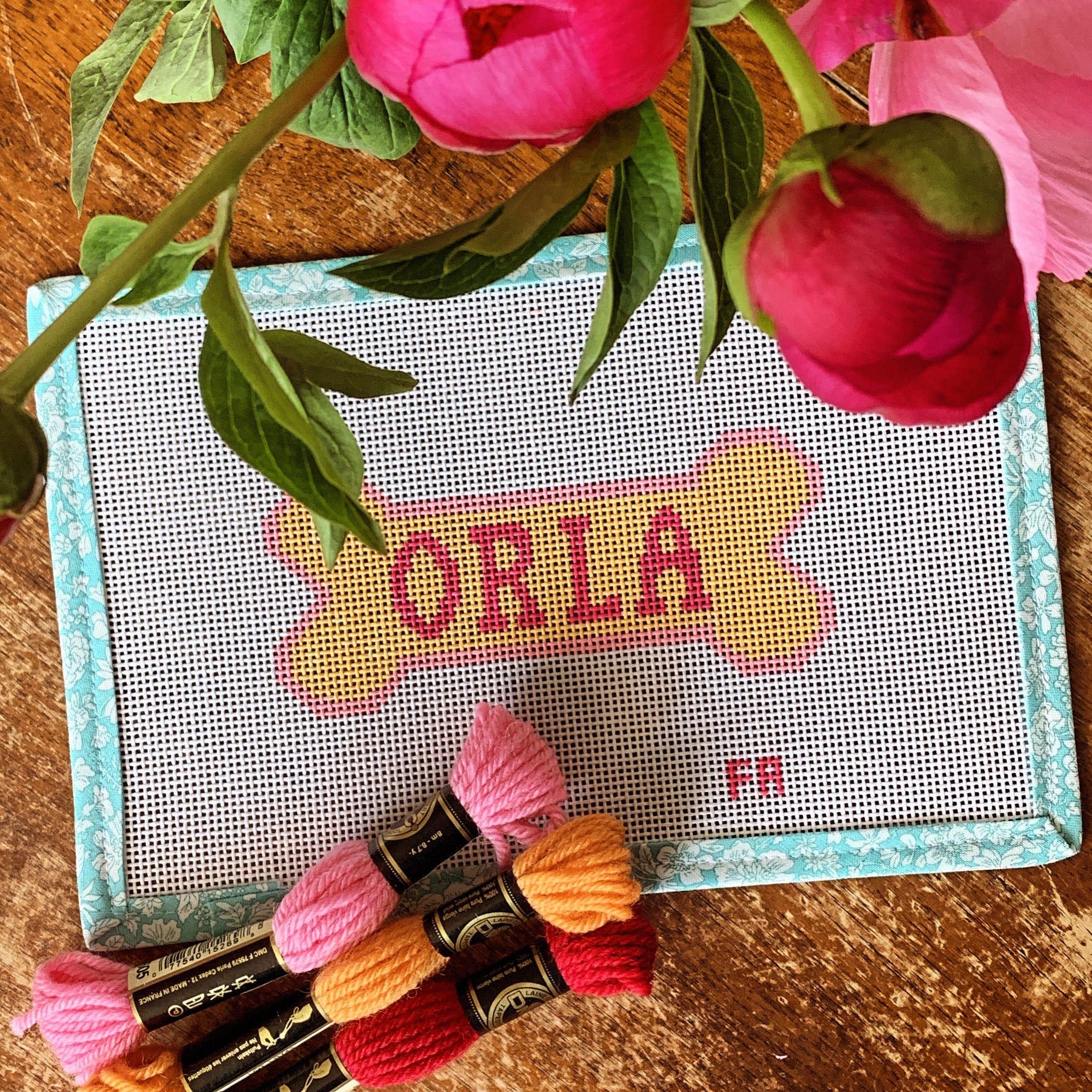 Custom dog bone needlepoint canvas with a yellow bone outlined in red, featuring space for a pet name, hand-painted on white 13 mesh with aqua floral trim.