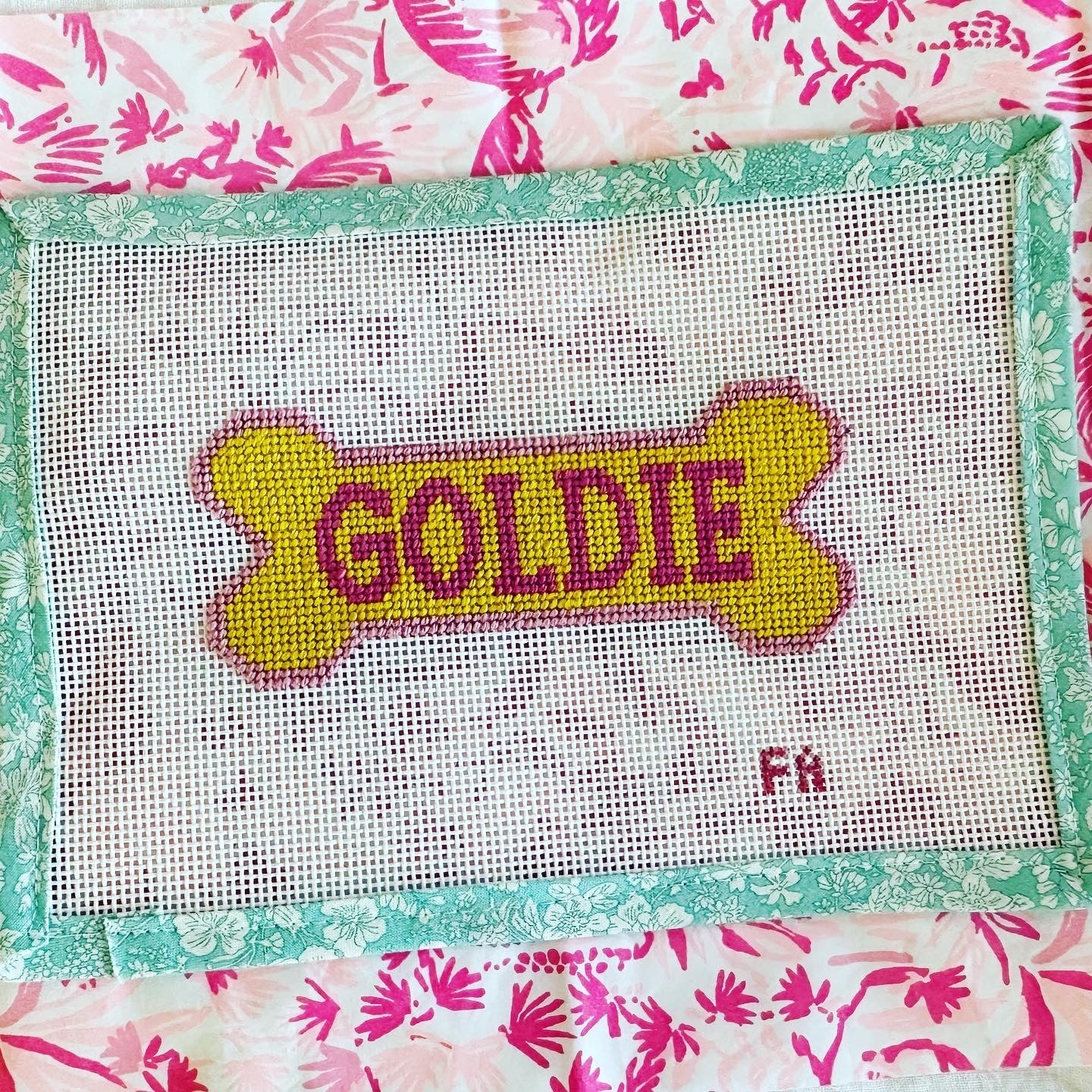 Custom dog bone needlepoint canvas with a yellow bone outlined in red, featuring space for a pet name, hand-painted on white 13 mesh with aqua floral trim.