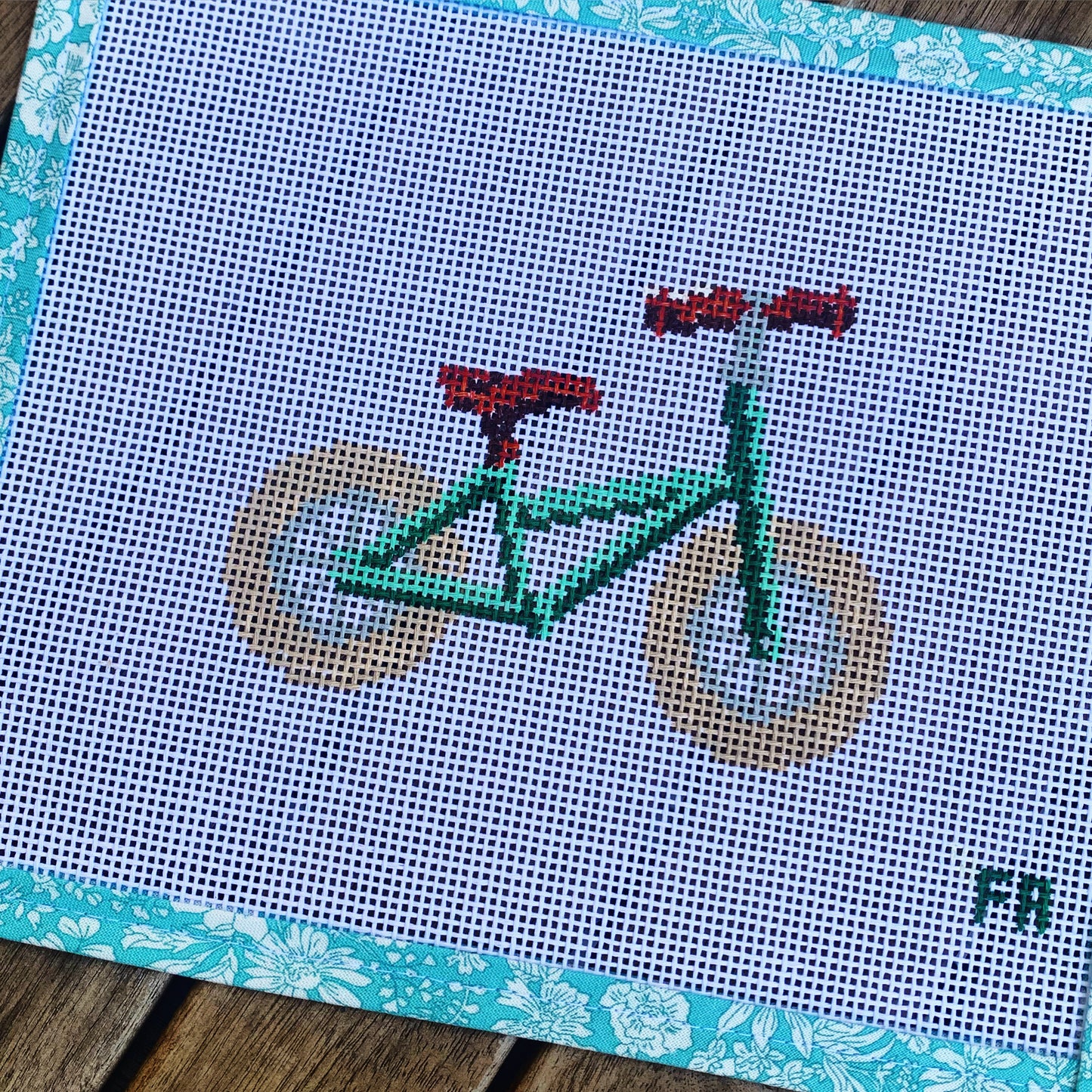 Green balance bike needlepoint canvas kit—stylized red toddler balance bike printed on natural 14-mesh canvas, 3¼ × 5″ DIY nursery décor project
