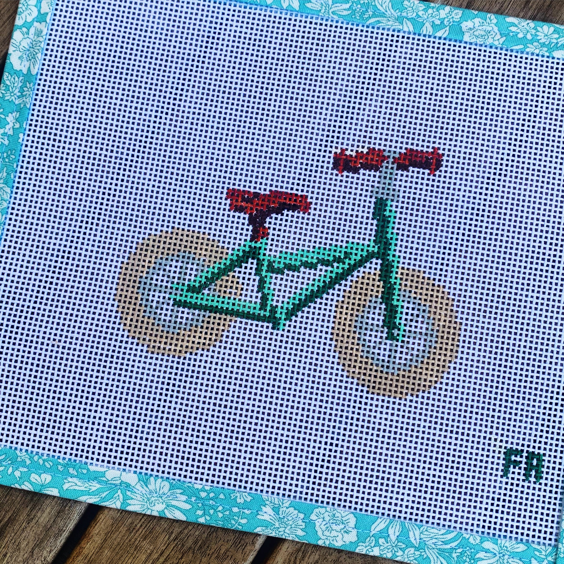 Green balance bike needlepoint canvas kit—stylized red toddler balance bike printed on natural 14-mesh canvas, 3¼ × 5″ DIY nursery décor project
