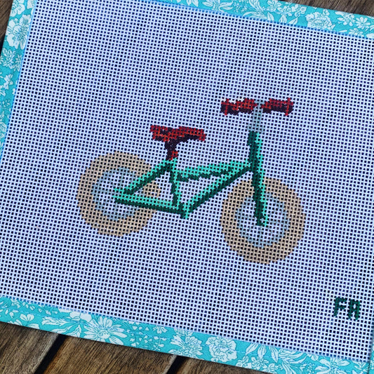 Green balance bike needlepoint canvas kit—stylized red toddler balance bike printed on natural 14-mesh canvas, 3¼ × 5″ DIY nursery décor project
