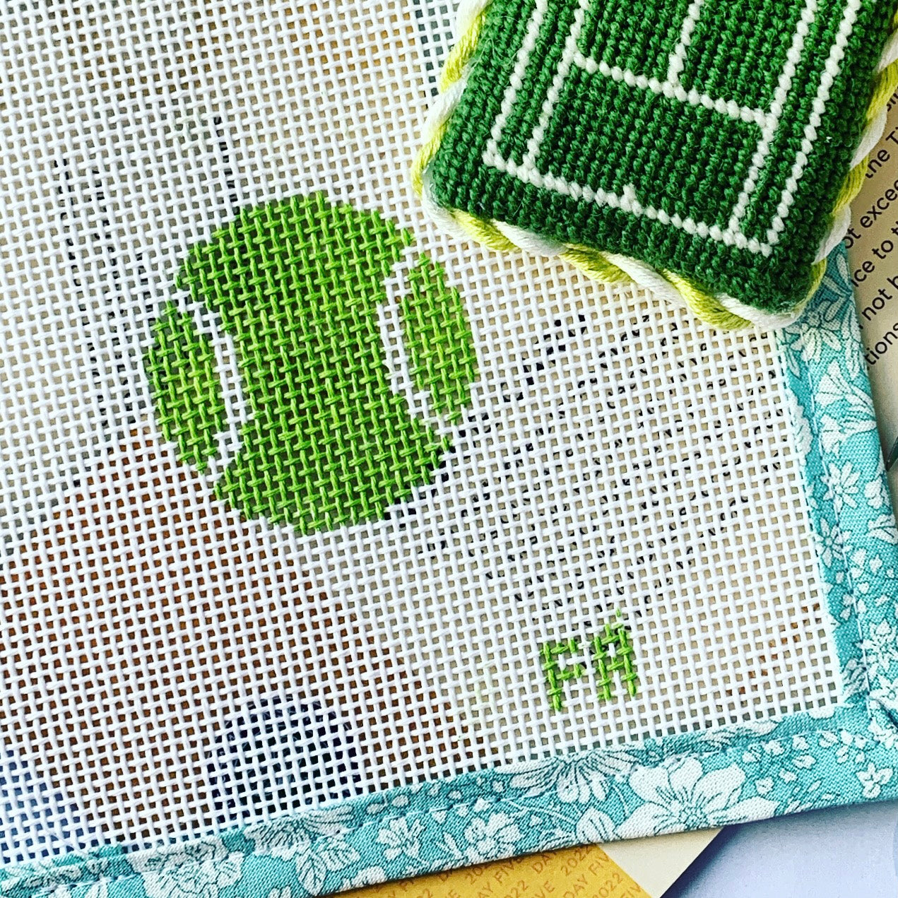 Mini tennis ball needlepoint canvas in bright yellow with simple white detail, perfect for sporty summer stitching.