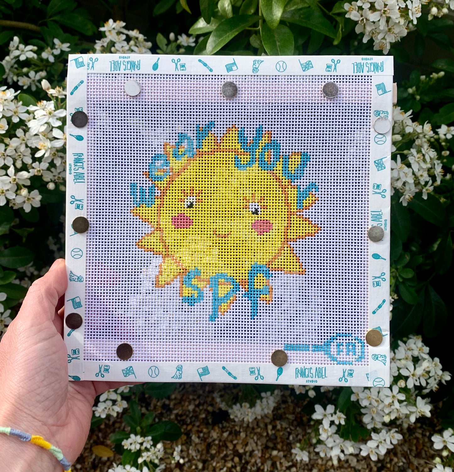 Friendly Sun “Wear Your SPF” needlepoint canvas kit—smiling yellow sun wearing sunglasses with bold “Wear Your SPF” text on natural 13-mesh canvas, 4½ × 4½″ DIY summer décor project
