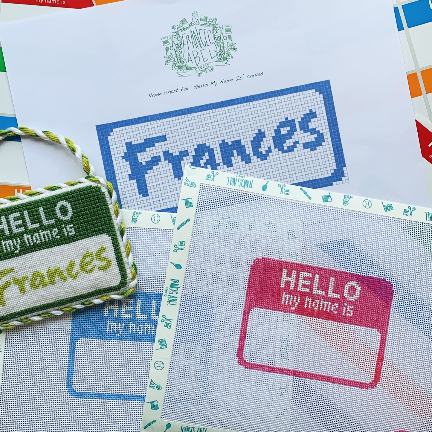Hello My Name Is needlepoint canvas kit—blue badge background with white “Hello My Name Is” heading and blank white name panel beneath, 4¼ × 3⅛″ on 18-mesh Zweigart canvas

