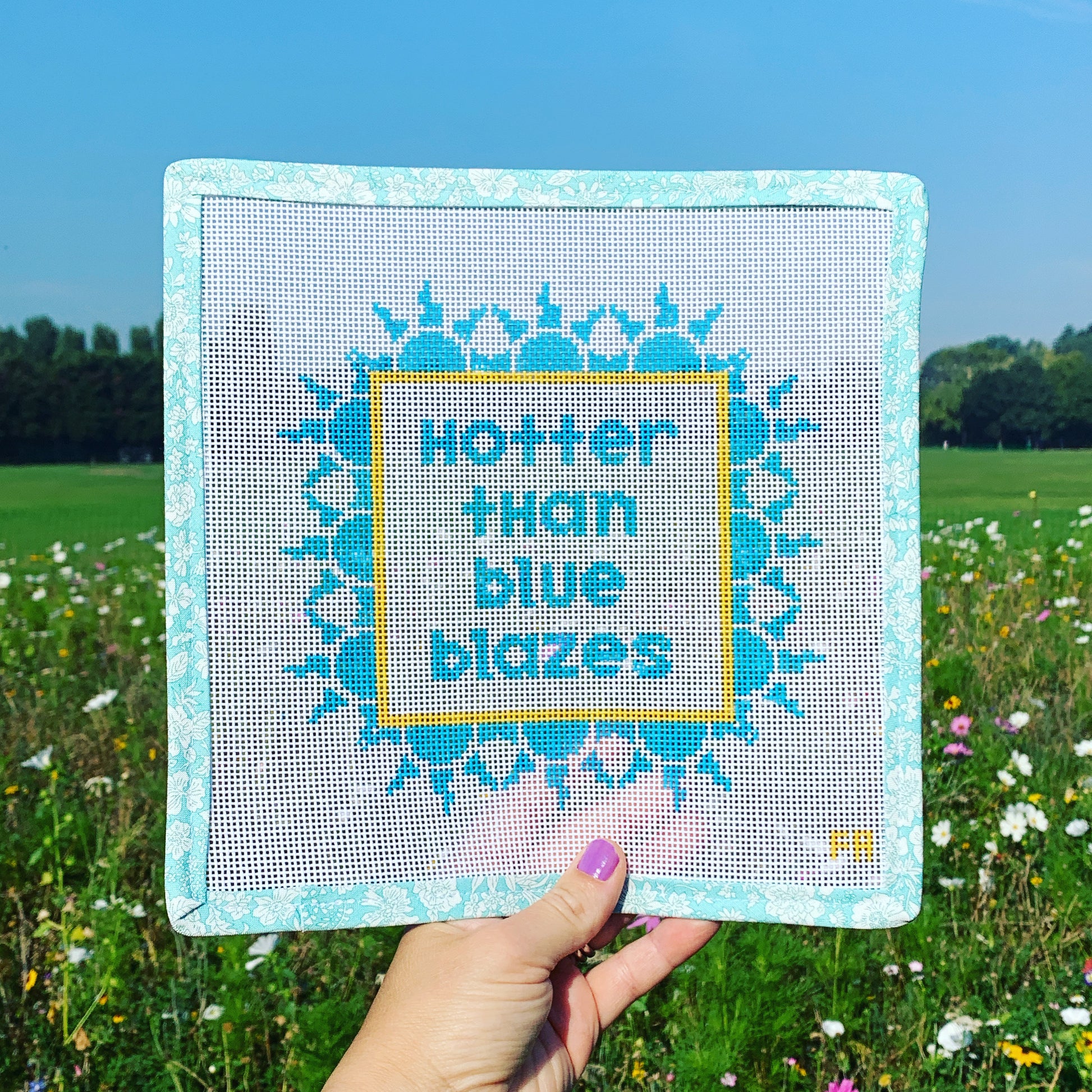 ‘Hotter than Blue Blazes’ needlepoint canvas kit—turquoise block lettering inside a yellow square border of stylized blue flame motifs on 13-mesh canvas 
