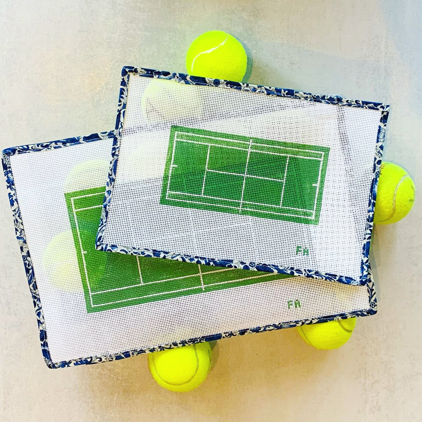 Tennis court clutch-size needlepoint canvas featuring a green court with white lines and pink border, hand-painted on 13 mesh.
