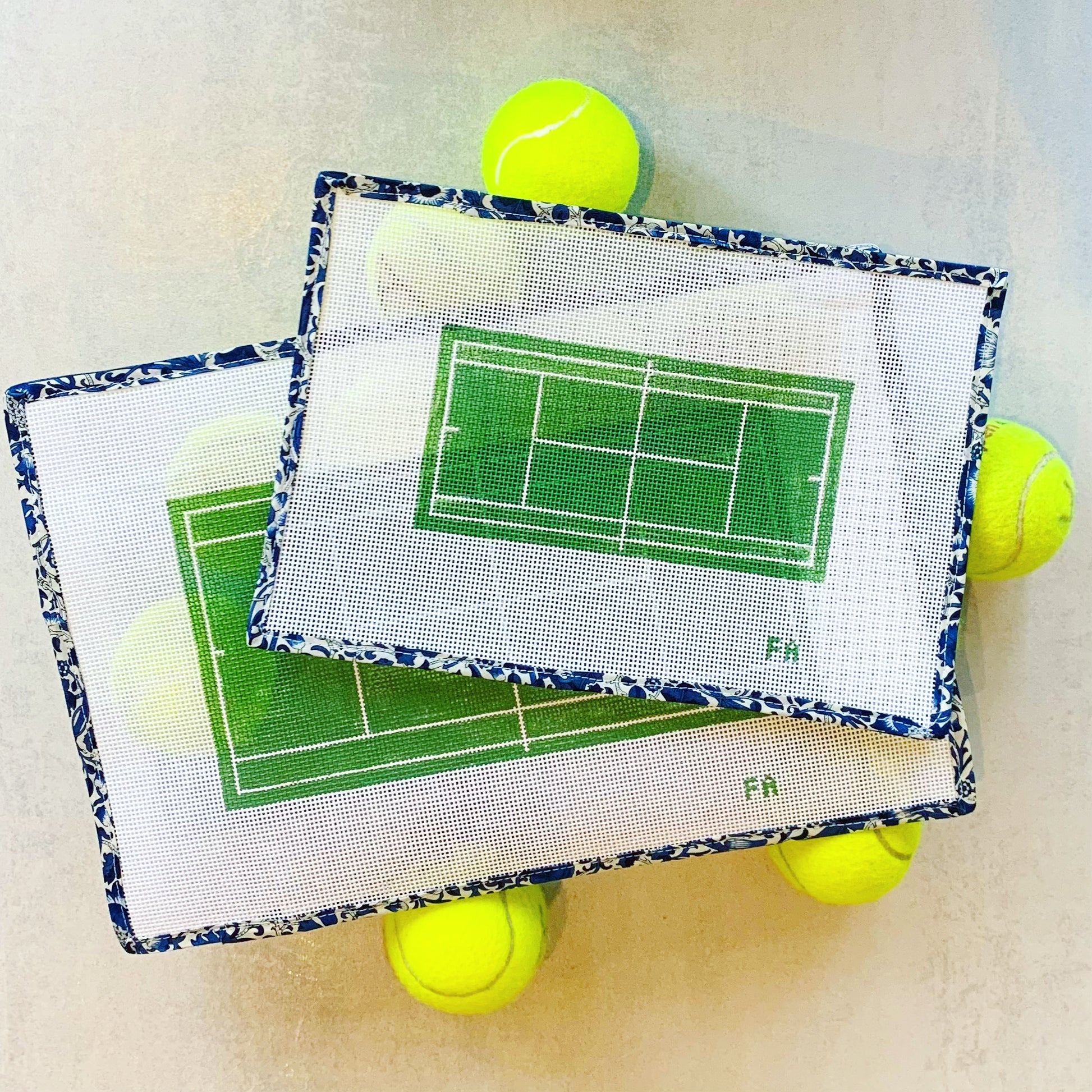 Tennis court clutch-size needlepoint canvas featuring a green court with white lines and pink border, hand-painted on 13 mesh.